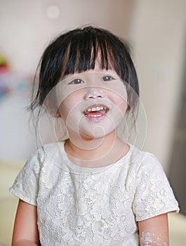 Portrait of cute little smile girl with baby powder on her face. Talcum concept