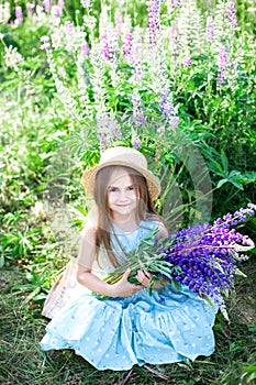 Portrait of a cute little smiling brunette girl with long beautiful hair in a straw hat, against the background of a flowering mea