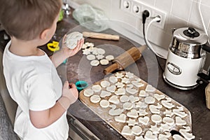 Portrait cute little toodler caucasian boy kid cooking sweet tasty cookies with young adult mother at home kitchen. Mom