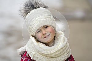 Portrait of cute little young funny pretty smiling blond child girl with gray eyes in nice warm winter clothing on white bright bl