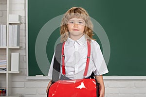 Portrait of cute, lovely, boy with backpack in school uniform in classroom. Back to school. Genius child, knowledge day.