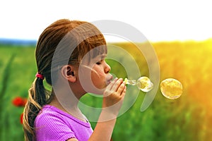 Portrait of cute lovely little girl blowing soap bubbles