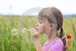 Portrait of cute lovely little girl blowing soap bubbles