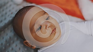 Portrait of cute mulatto baby with funny face expression relaxing on the blanket