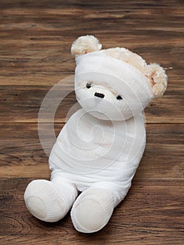 Portrait of cute mummy teddy bear doll bind with white gauze or bandage on dark wooden background