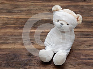 Portrait of cute mummy teddy bear doll bind with white gauze or bandage on dark wooden background