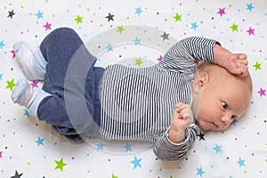 Portrait of a cute newborn baby who lies on his back in crib, to photo