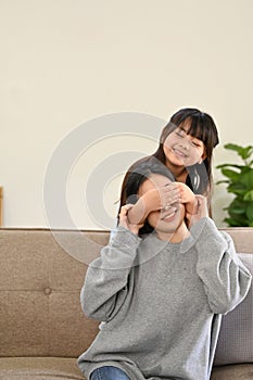 Portrait, Cute and playful young Asian girl surprising or playing peek a boo with her mom