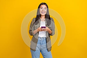 Portrait of cute positive girl with long hairdo wear khaki shirt instagram facebook twitter whatsapp isolated on yellow