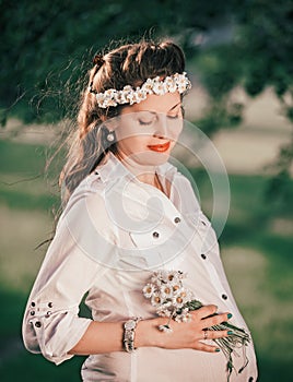 Portrait of a cute pregnant woman with a bouquet of daisies