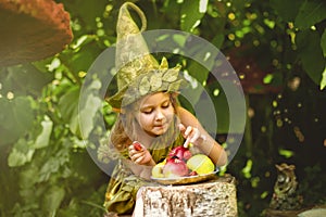 Portrait of a cute pretty girl in a gnome eats berries and apples on a plate.