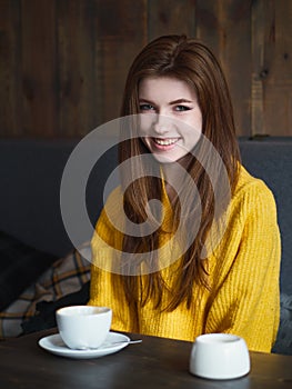 Portrait of a cute pretty redhead smiling woman sitting in a cafe enjoying free time coffee break with a cup of cappuccino