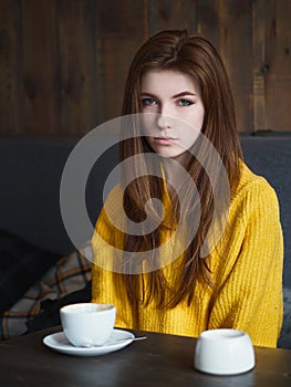 Portrait of a cute pretty redhead woman sitting in a cafe enjoying free time coffee break with a cup of cappuccino