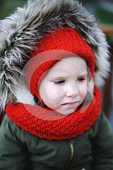 Portrait of cute sad little girl in warm outerwear clothing outdoors alone