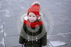 Portrait of cute sad little girl in warm outerwear clothing standing outdoors alone in cool weather