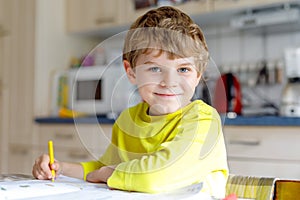 Portrait of cute school kid boy at home making homework. Little concentrated child writing with colorful pencils