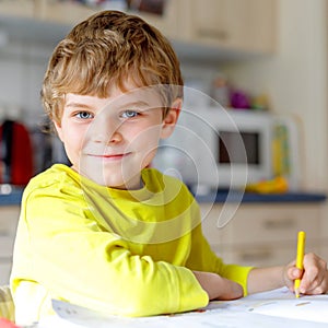 Portrait of cute school kid boy at home making homework. Little concentrated child writing with colorful pencils
