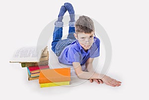 Portrait of cute schoolboy sitting with books and typing on laptop keyboard