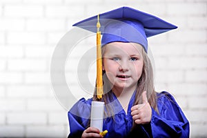 Portrait of cute schoolgirl with graduation hat in classroom
