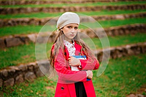 Portrait of cute schoolgirl with interesting book in natural environment