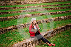 Portrait of cute schoolgirl with interesting book in natural environment