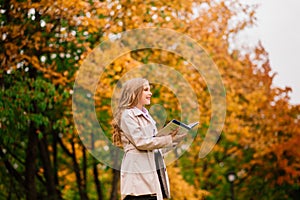 Portrait of cute schoolgirl with interesting book in natural environment