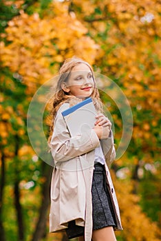 Portrait of cute schoolgirl with interesting book in natural environment