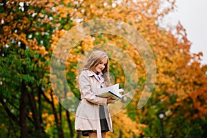 Portrait of cute schoolgirl with interesting book in natural environment