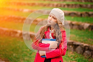 Portrait of cute schoolgirl with interesting book in natural environment