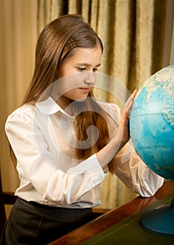 Portrait of cute schoolgirl looking at Earth globe