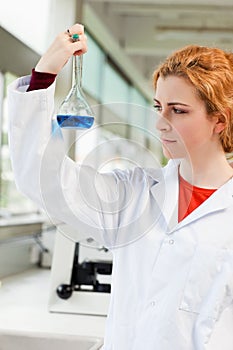 Portrait of a cute scientist holding a blue liquid