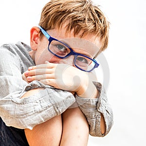 Portrait, cute shy boy with freckles hiding smile in knees