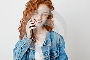 Portrait of cute shy redhead girl smiling looking in side over white background. Copy space.