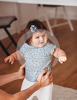 Portrait of cute small  baby girl learn walking at home holding dad hands, little  toddler infant child make do first steps with