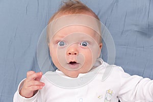 Portrait of cute smiling baby lying on the bed at home, top view