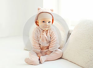 Portrait cute smiling baby sitting in white room at home