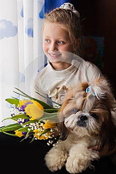 Portrait of a cute smiling girl with a bouquet of colorful flowers. Girl hugging a dog. Girl and dog at home