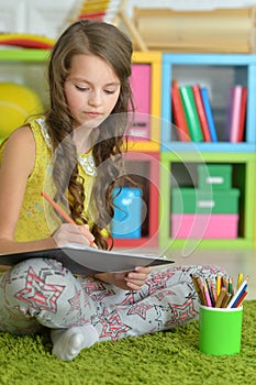 Portrait of cute smiling girl drawing at home