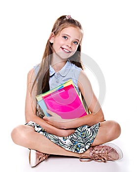 Portrait of cute smiling happy little school girl child teenager sitting on a floor and holding the books isolated