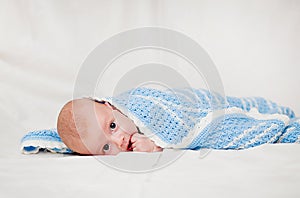 Portrait of a cute smiling infant baby crawling in a diaper, two-month baby child holds head