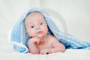 Portrait of a cute smiling infant baby crawling in a diaper, two-month baby child holds head