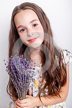 Portrait of cute smiling little girl with bunch of lavender flowers