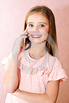 Portrait of cute smiling little girl calling by cell phone smar