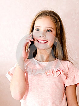 Portrait of cute smiling little girl calling by cell phone smar
