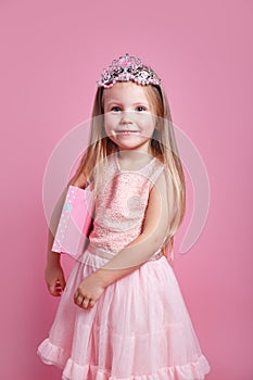 Portrait of cute smiling little girl with gift box in princess dress and crown