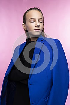 Portrait of a cute smiling teen girl wearing a dark turtleneck and a blue jacket blazer. Pink background. Advertising, trendy and