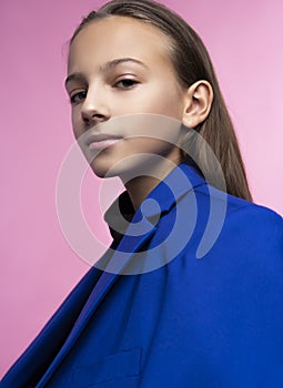 Portrait of a cute smiling teen girl wearing a dark turtleneck and a blue jacket blazer. Pink background. Advertising, trendy and