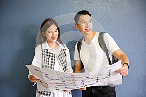 Portrait of cute smiling young adult Asian couples tourists on white and black clothes standing and holding paper map together