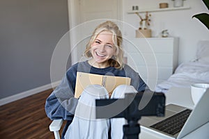 Portrait of cute, smiling young social media content creator, girl records video on digital camera and stabiliser, holds