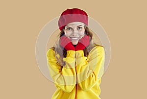 Portrait of cute smiling young woman in autumn clothes holding her hands near her face.